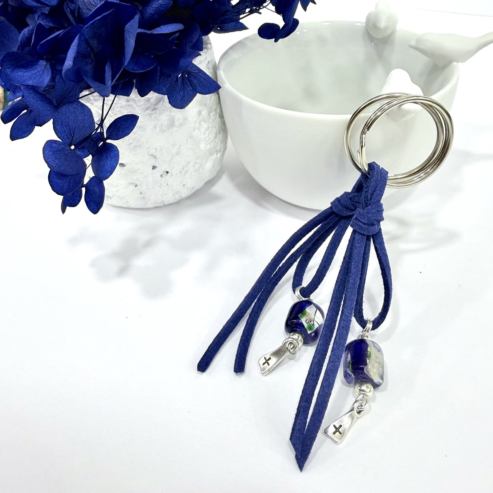 GP.84 Μπρελόκ σουέτ με γυαλωμένη χάντρα και επάργυρο σταυρό.